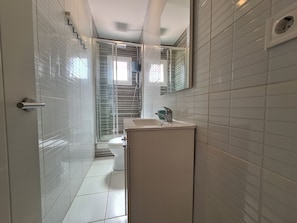 A modern bathroom with a glass shower enclosure, a white sink, and a toilet.