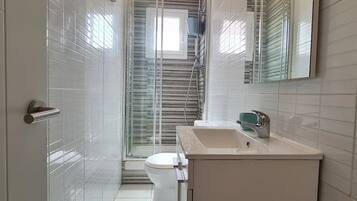 A modern bathroom with a toilet, sink, and shower.