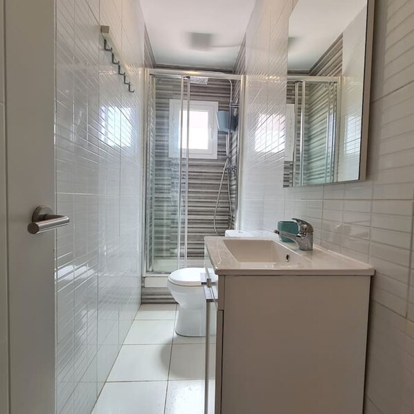 A modern bathroom with a toilet, sink, and shower. - Walk to Camp NOU - Wi-fi AC 3 Bed by Myrentalhost (L'Hospitalet de Llobregat)