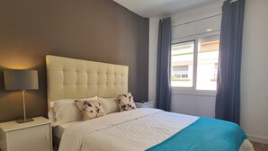 A bedroom with a bed, nightstand, lamp, and a view of the outside. - Walk to Camp NOU - Wi-fi AC 3 Bed by Myrentalhost (L'Hospitalet de Llobregat)