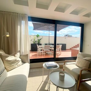 A modern living room with a sofa, a coffee table, and a dining area with chairs and a table. - Modern Penthouse With Views Near Paseo De Gracia By Myrentalhost (Barcelona)