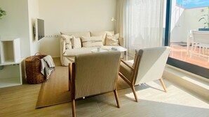 A modern living room with a sofa, a dining table, and chairs. There is a large window with curtains, a floor lamp, and a basket on the floor. - Modern Penthouse With Views Near Paseo De Gracia By Myrentalhost (Barcelona)