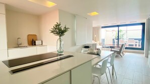 A modern kitchen with a central island, a dining area with chairs, and a view to the outside. - Modern Penthouse With Views Near Paseo De Gracia By Myrentalhost (Barcelona)