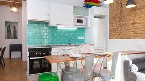 Une cuisine moderne avec des meubles blancs, un pare-feu vert et un coin repas où les chaises ne sont pas assorties.