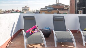 Eine Dachterrasse mit zwei Liegestühlen und einem bunten Handtuch.