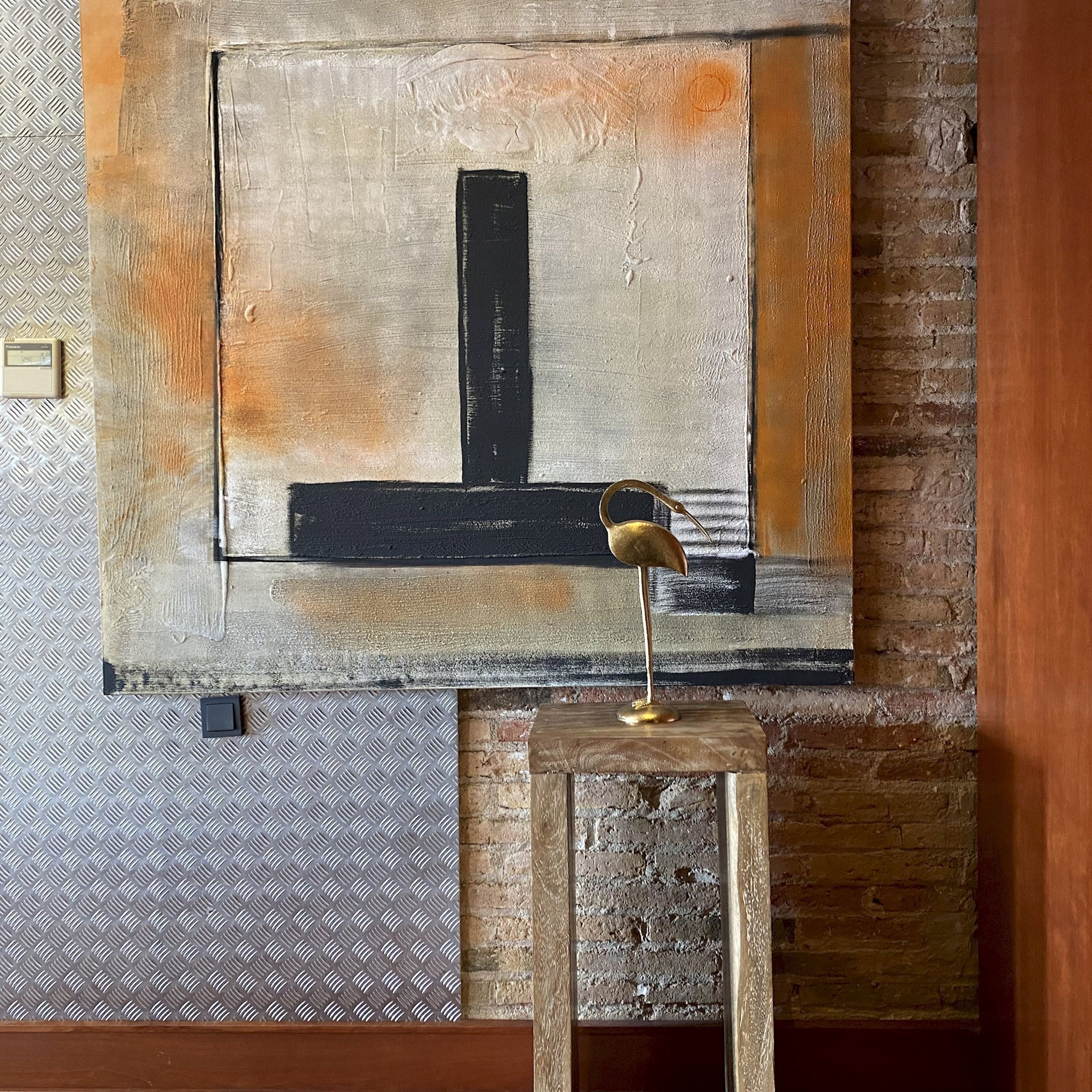 A painting with a black vertical stripe on a textured wall.