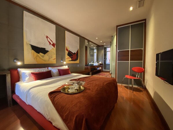 A modern hotel room with a large bed, a TV, a bathroom, and artwork on the walls. - Luminous Designer Loft Style Apt Eixample Views By Myrentalhost (Barcelona)