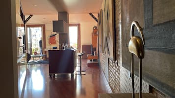 Un vestíbulo amplio con suelo de madera, una recepción y una gran escultura en la pared.