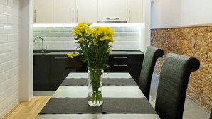 A modern kitchen with white cabinets, a black countertop, and a vase with yellow flowers on the dining table. - Unique Architects Apartment IN Trendy Central Poble SEC By Myrentalhost (Barcelona)