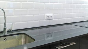 A kitchen with white subway tiles, a stainless steel sink, and black cabinets. - Unique Architects Apartment IN Trendy Central Poble SEC By Myrentalhost (Barcelona)