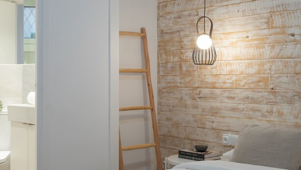 A bedroom with a wooden wall, a ladder, a bedside table with books, and a bed with a blue blanket. - Vicens Gem Private Terrace HS Wi-fi in Gracia by Myrentalhost (Barcelona)