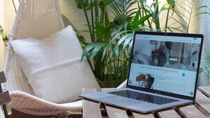 A laptop on a wooden table with a wicker chair and a hanging hammock in a green plant-filled area. - Vicens Gem Private Terrace HS Wi-fi in Gracia by Myrentalhost (Barcelona)