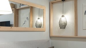A modern living room with a grey sofa, two cushions, a wooden-framed mirror, and two hanging lamps. - Vicens Gem Private Terrace HS Wi-fi in Gracia by Myrentalhost (Barcelona)