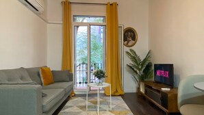 A living room with a sofa, a small table, a TV, and a potted plant.