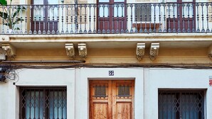 A building with a wooden door, two windows with metal bars, and a balcony with ornate railings. - Charming Modern Apt in Trendy Gracia 5PP by Myrentalhost (Barcelona)