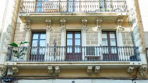 A multi-story building with ornate balconies, a wooden door, and barred windows. - Charming Modern Apt in Trendy Gracia 5PP by Myrentalhost (Barcelona)