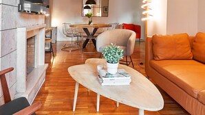 A modern living room with a fireplace, a dining area, and a TV mounted on the wall. - Love Local Life Near Sagrada Familia By Myrentalhost (Barcelona)
