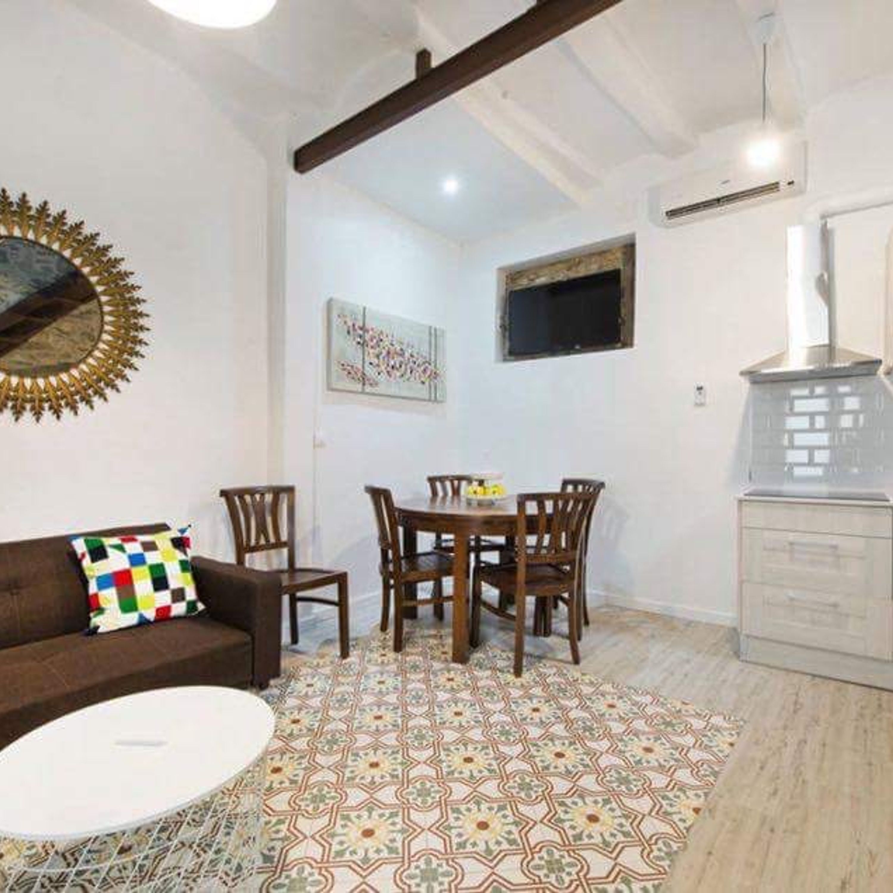 Una sala de estar con un sofá marrón, una mesa redonda para café, una mesa de comedor con sillas, un piso con diseño, un ventilador de techo y una chimenea.