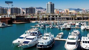 A marina with multiple boats docked, surrounded by urban buildings and a clear sky. - Barcelona Gem Penthouse By Myrentalhost (Barcelona)