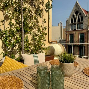 An outdoor seating area with wicker furniture, a potted plant, and decorative glassware. - Barcelona Gem Penthouse By Myrentalhost (Barcelona)