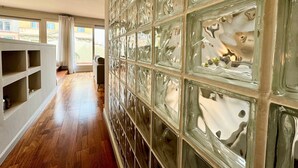 A hallway with a glass block wall, wooden flooring, and a view of the outside. - Barcelona Gem Penthouse By Myrentalhost (Barcelona)
