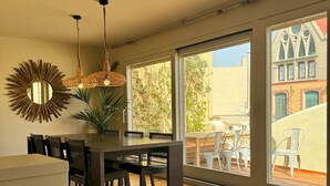 A dining area with a wooden table and chairs, a hanging light fixture, and a large mirror on the wall. - Barcelona Gem Penthouse By Myrentalhost (Barcelona)