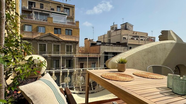 A wooden deck with a table, cushions, and a potted plant. - Barcelona Gem Penthouse By Myrentalhost (Barcelona)