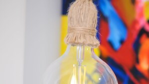 Een glazen fles met kurksluiting, afgebeeld tegen een kleurrijk abstract schilderij.
