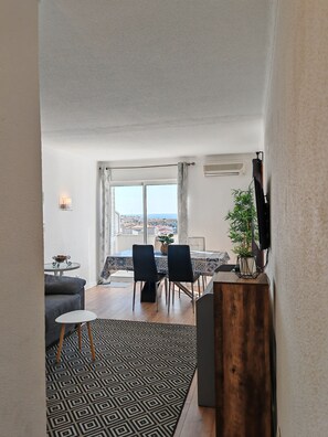 Ein modernes Wohnzimmer mit Essbereich, großen Fenstern und Blick auf die Stadt.