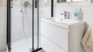 Une salle de bain moderne avec une douche à parois de verre, un meuble-lavabo blanc et un grand miroir.