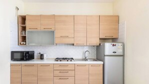 Une cuisine de taille réduite, dotée d’armoires en bois, d’un four à micro-ondes, d’une cuisinière, d’un évier et d’un réfrigérateur.