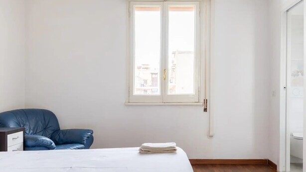 Une chambre à coucher avec un lit, une chaise, une fenêtre et une porte.