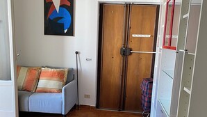 Une pièce comprenant un canapé, une armoire en bois, une porte et un tableau abstrait accroché au mur.