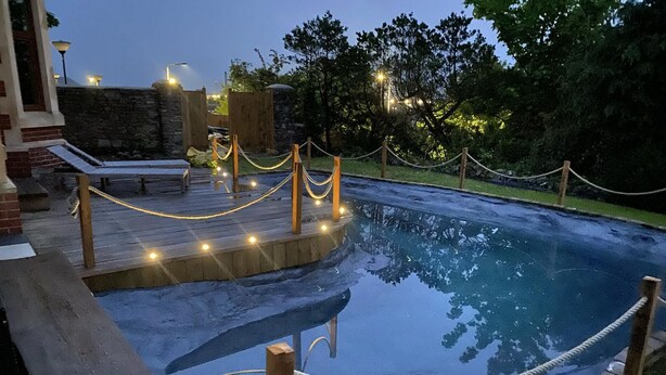 Une piscine dotée d’une terrasse en bois et d’une barrière en corde.