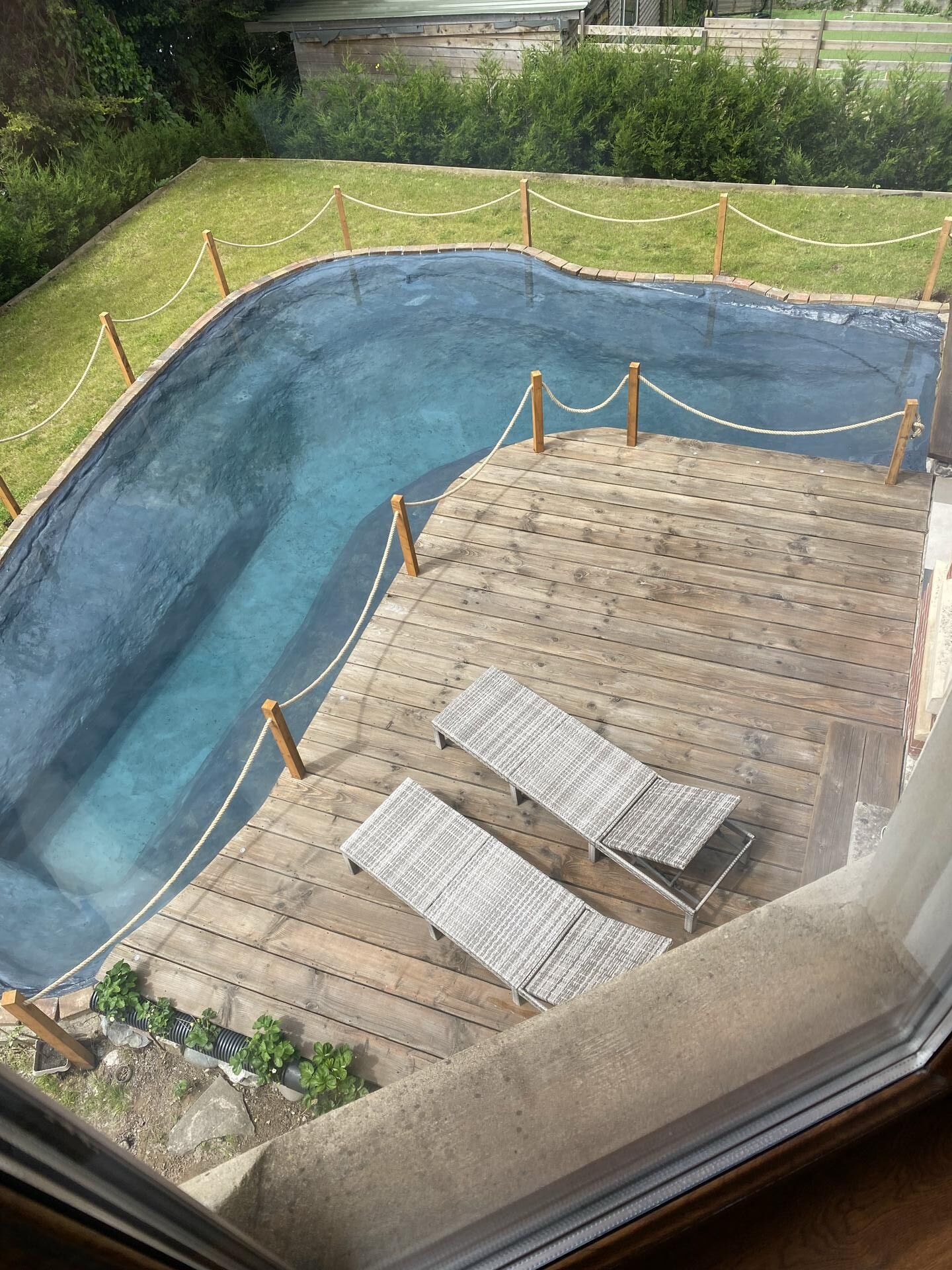 Ein Schwimmbecken mit Holzterrasse und Liegestühlen.
