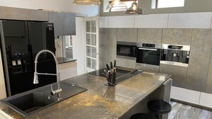 Une cuisine moderne dotée d’appareils électroménagers en acier inoxydable, d’un plan de travail en granit et de tabourets de bar.