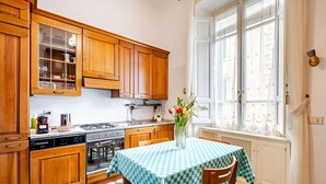 A kitchen with wooden cabinets, a stove, and a table with a checkered tablecloth. - Vaticano - Saint Peter-Elegant apartment (Roma)
