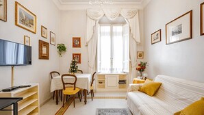 A well-lit living room with a dining area, a television, and a sofa with a yellow pillow. - Vaticano - Saint Peter-Elegant apartment (Roma)