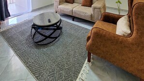 A living room with a sofa, armchair, and a round coffee table. - Elite Homes (Kampala)