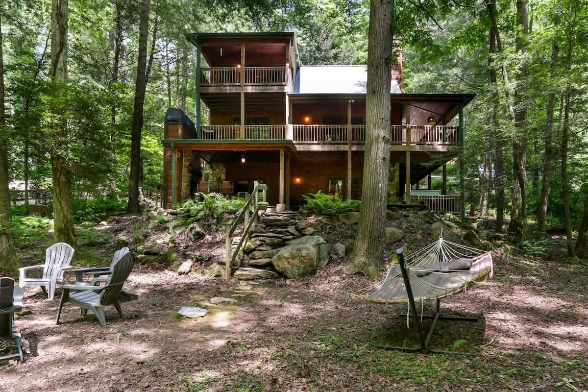 A cabin with a balcony, a hammock, and a dining area with chairs.
