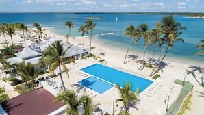 Un resort con piscina, playa y palmeras.