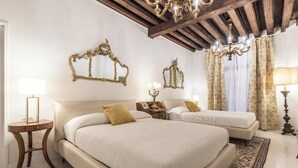 A hotel room with two beds, ornate mirrors, a chandelier, and a classic chandelier.