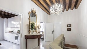 A spacious living area with a wooden staircase, a chandelier, and a large mirror.