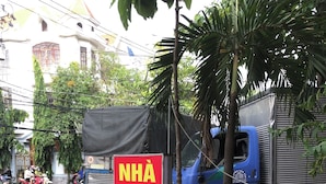 A signboard with text and a blue truck parked on the side of a road. - Happy Motel (Bien Hoa)