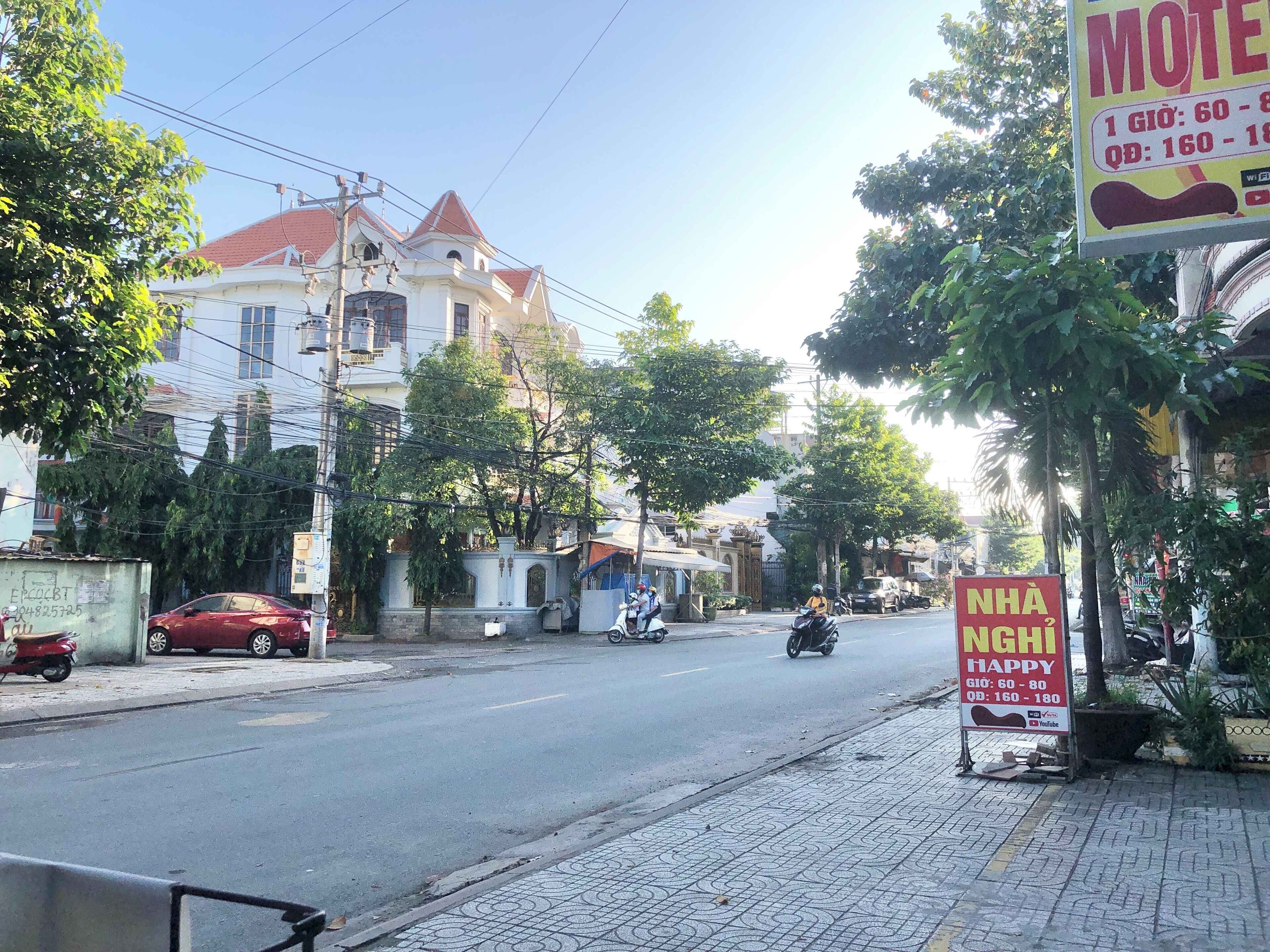 Eine Straße mit einem Schild für ein Motel, ein rotes Auto parkte am Straßenrand und ein Motorrad fährt vorbei.