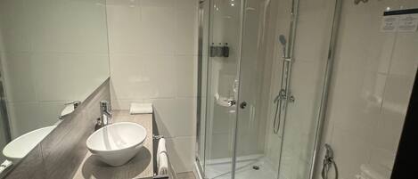 A modern bathroom with a glass-enclosed shower, a sink, and a toilet.