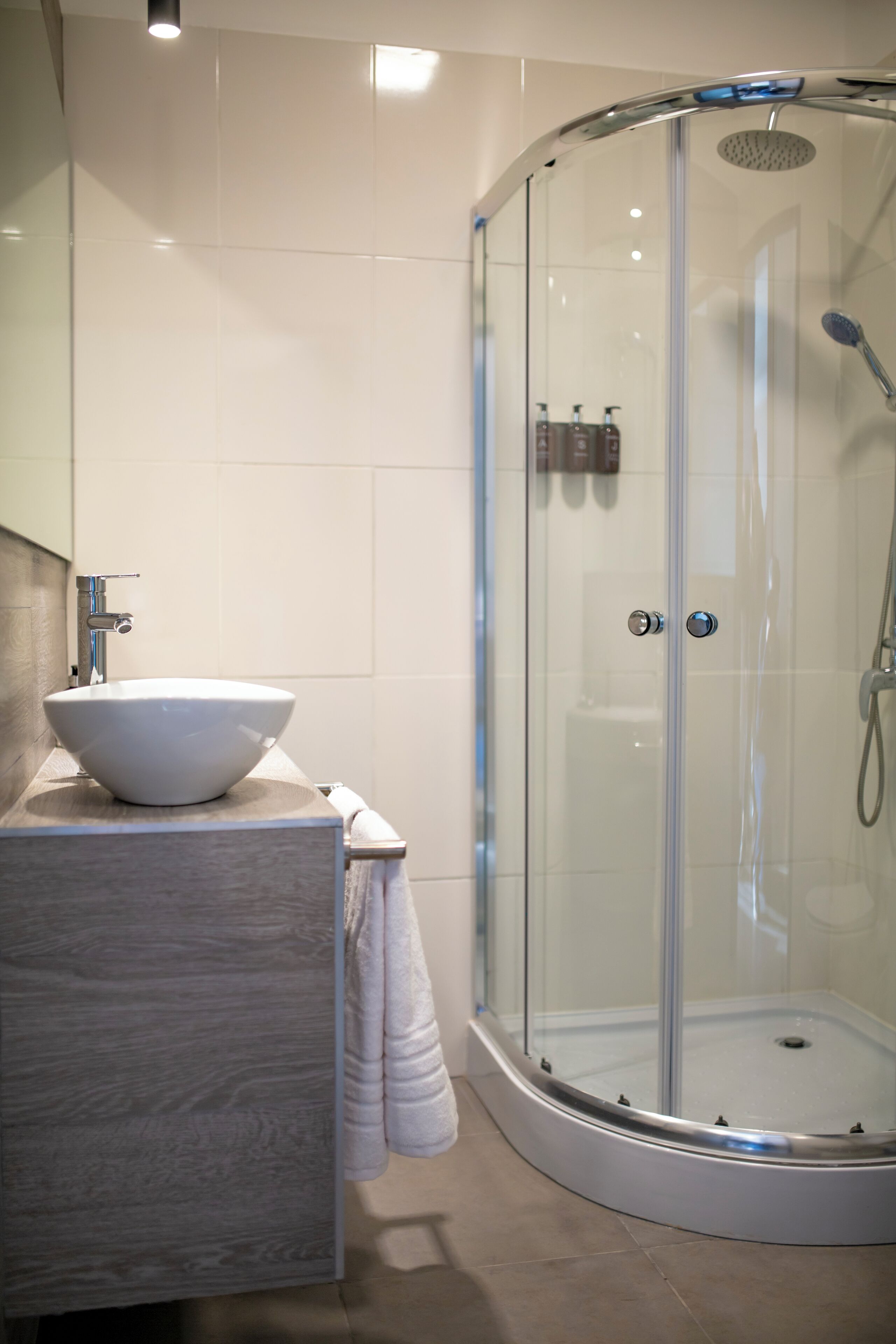 Un baño moderno con ducha de vidrio, lavamanos blanco y tocador de mármol.
