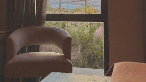A room with a bed, a chair, and a window with a view of a sunset and a bridge. - Amerian Chacras de Coria (Chacras de Coria)
