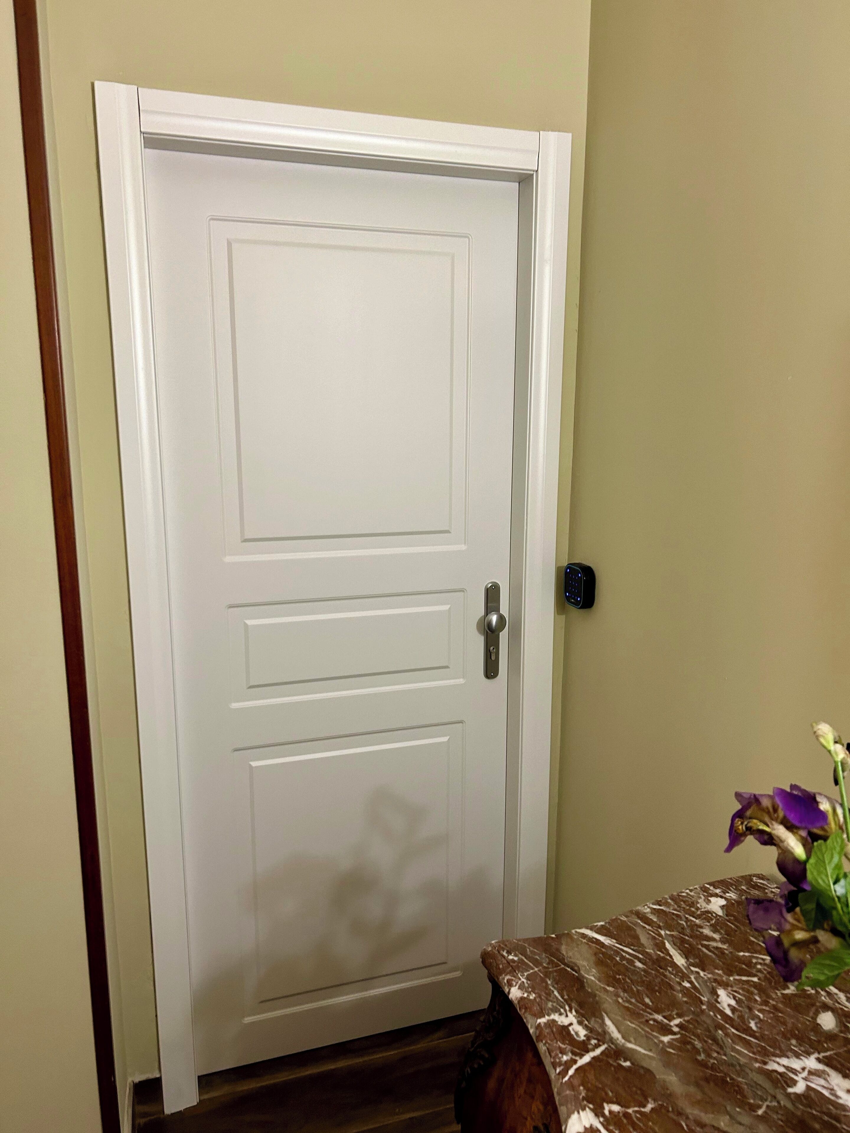 A closed white door with a silver handle and a keyhole.