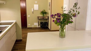 A modern kitchen with a central island, pendant lights, and a vase with flowers. - Domus Ballà Tonale Camera 1 (Verona)